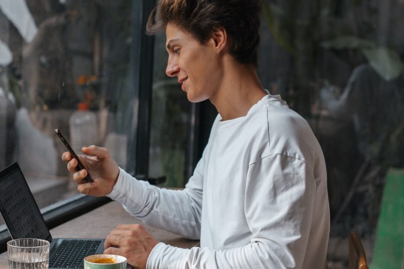 Man holding phone Laptop